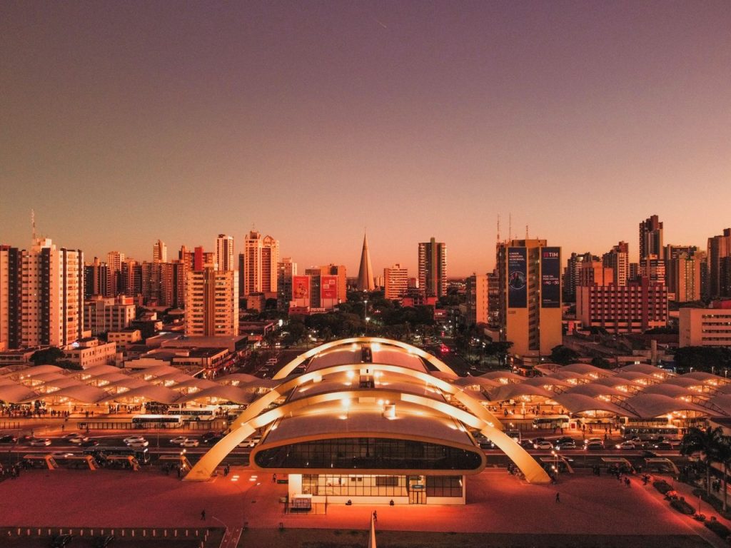 O que a marca de 432.635 moradores revela sobre Maringá em 2026 Vista aérea de Maringá ao entardecer, com o terminal intermodal e a área urbana da cidade em destaque.