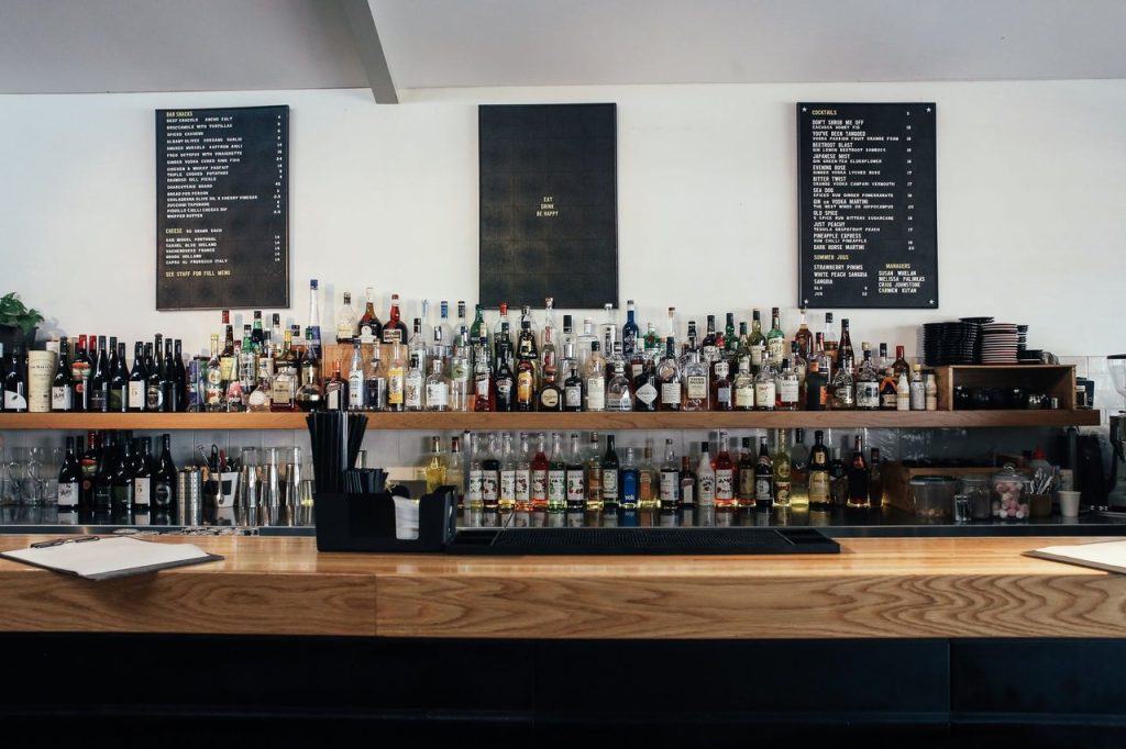 Balcão de bar com diversas garrafas de bebidas alcoólicas expostas em prateleiras.