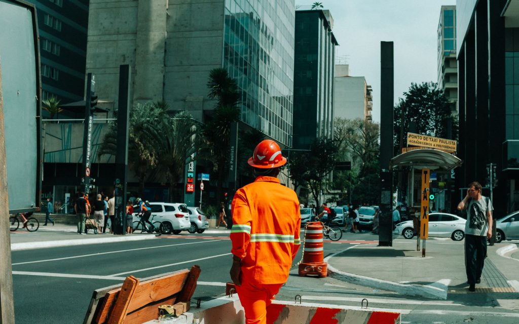 Trabalhador da construção em uma movimentada cena urbana de São Paulo.